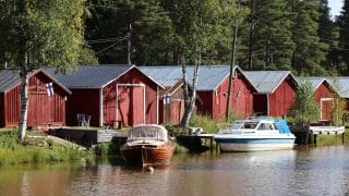 Sunti ja sen takana olevia punaisia venevajoja. Venevajojen edessä on kaksi laituriin kiinnitettyä venettä.
