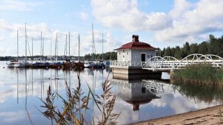 Bild från stranden av ungdomscentret Villa Elbas bryggbastu. Bakom bastun finns många segelbåtar förtöjda vid båtbryggan. I bakgrunden syns skogen på motsatta stranden.