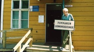 Veikko Salkio kannattelee Pummangin luonnonsuojelualueen kylttiä Kiepin edustalla 2000-luvun alussa.
