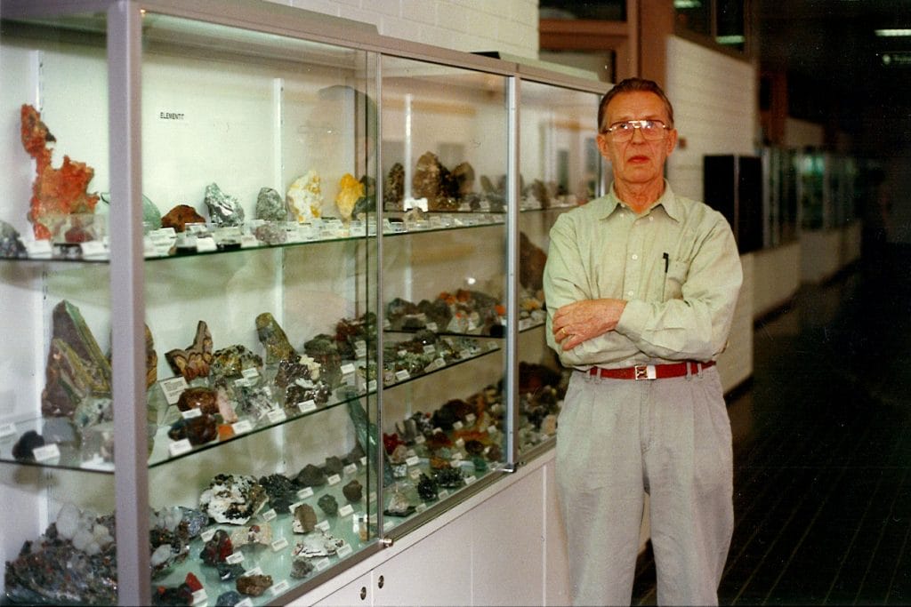 Nissinen stands beside mineral showcases.