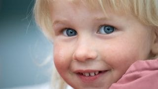 En liten flicka ser mot kameran