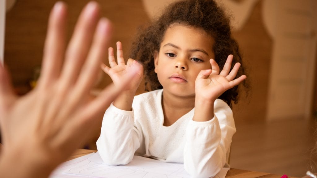 A little girl is learning to count with fingers.