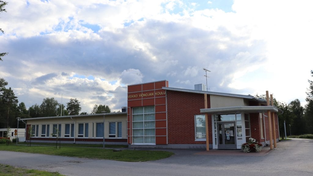 Veikko Vionojan koulurakennus kesäisenä pilvisenä päivänä.