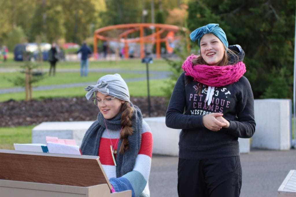 En flicka spelar piano och en flicka sjunger i parken.