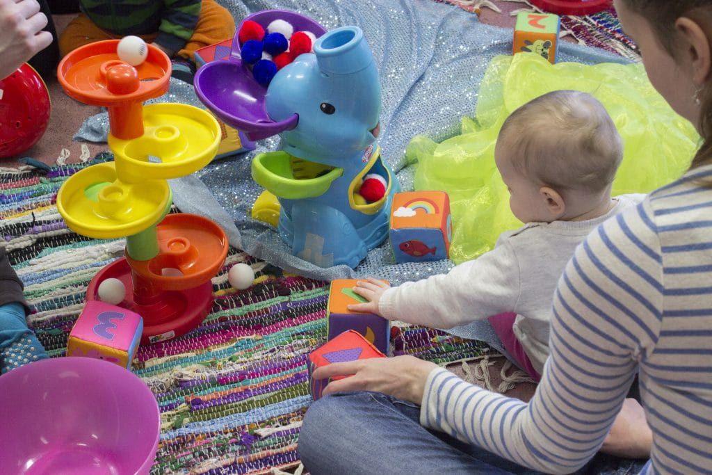 Vauva tutkimassa värikkäistä materiaaleja