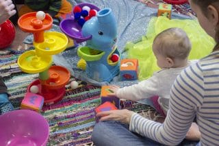 Vauva tutkimassa värikkäistä materiaaleja