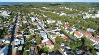 Flygfoto taget ovanför Neristan. I förgrunden syns Karlebys gamla stadsdel med sina gator, gårdar och byggnader. Lite längre bort syns Idrottsgården och bakom den vattentornet. Långt i horisonten skimrar havet.
