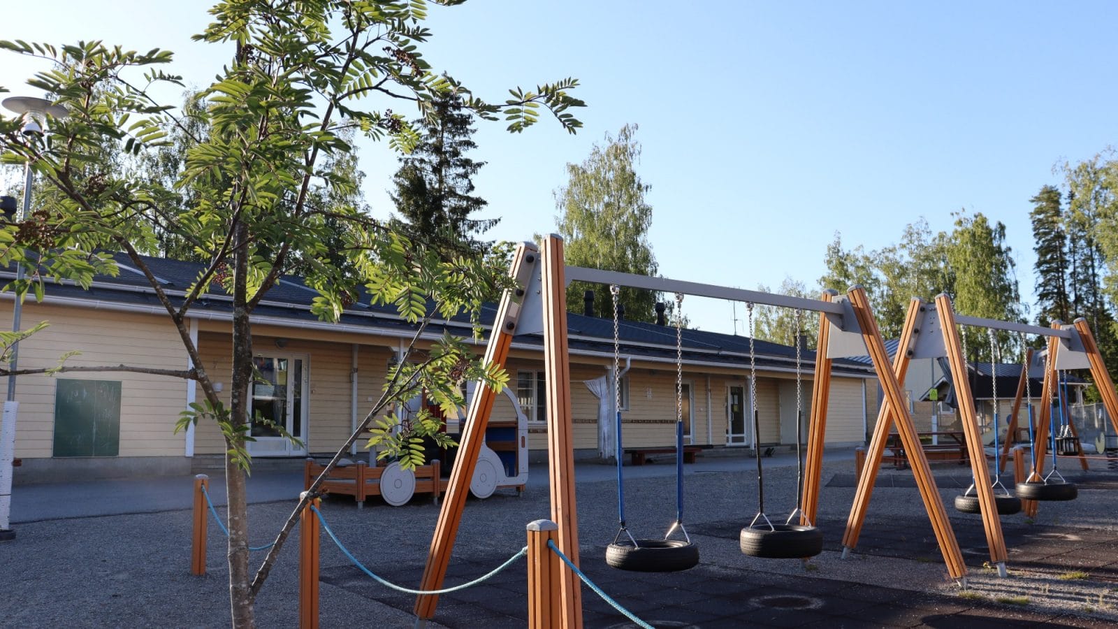 Ruotsalon päiväkotirakennus, jossa etualalla lasten keinuja.