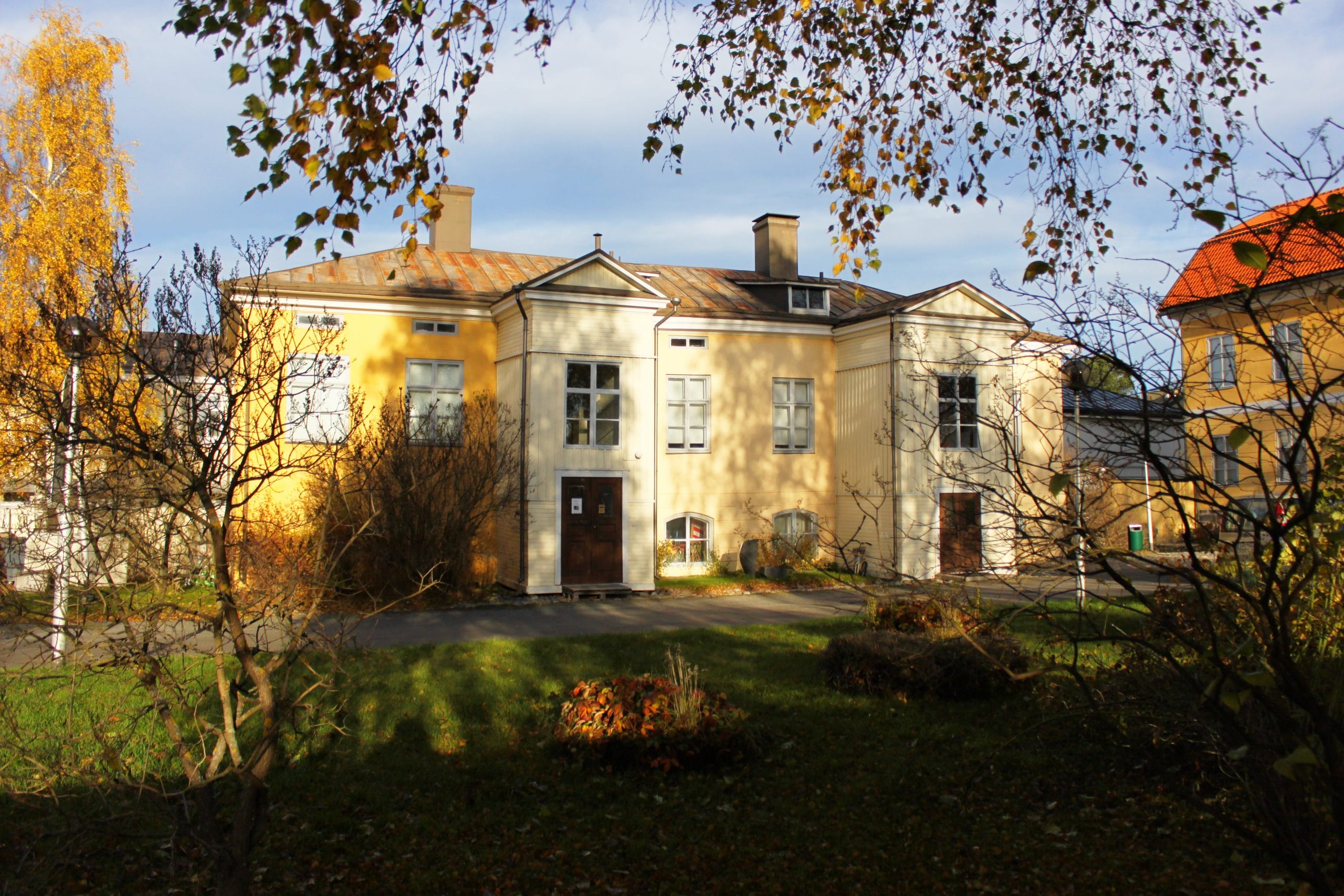 Kaksikerroksinen vanha kivirakennus syyspäivänä kuvattuna.