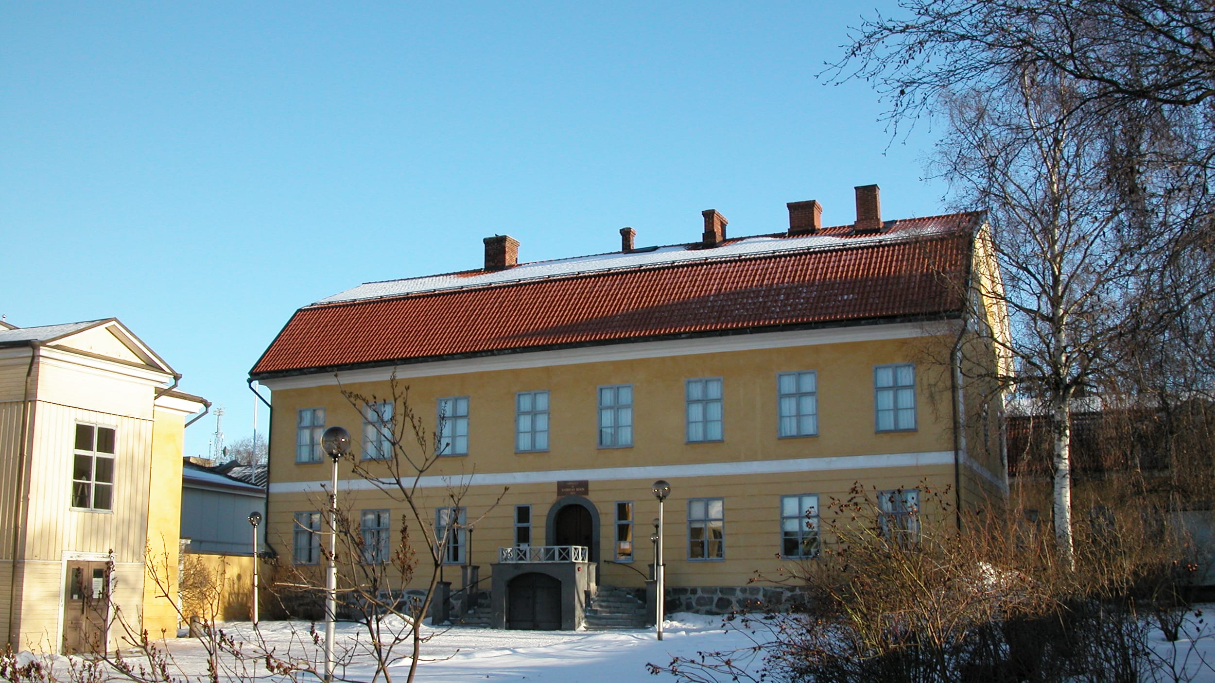 Suuri, keltainen kivirakennus on kuvattu aurinkoisena talvipäivänä.