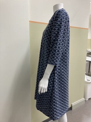 Naisen mekko, tummansinisellä pohjalla valkoisia aaltokuvioita. Sivukuva.