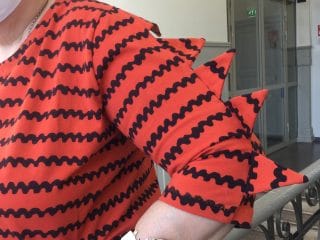 Naisen trikoopusero, jossa hihoissa kolmiokoristelu.