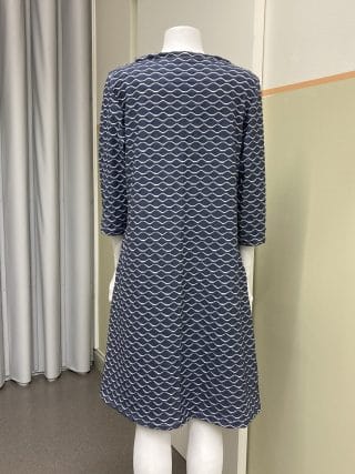 Naisen mekko, tummansinisellä pohjalla valkoisia aaltokuvioita. Kuva takaa.