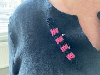 Käsinvirkattu pinkkiharmaa koru.