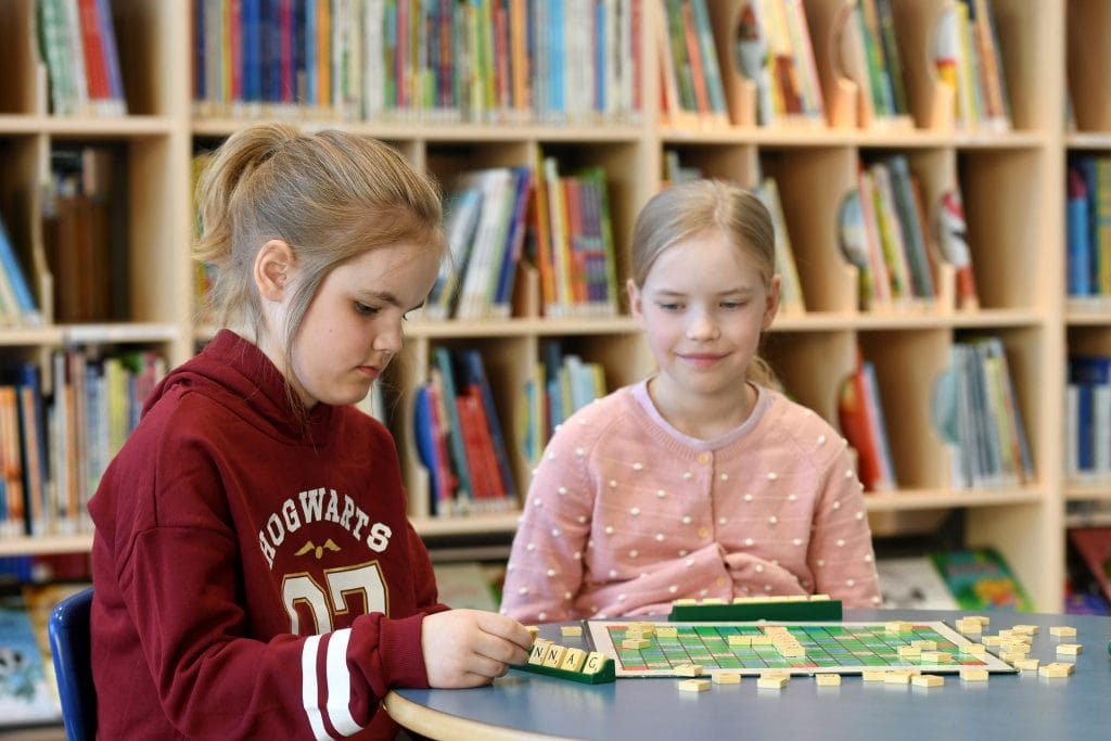 Kaksi nuorta työttöä pelaa Scrabble-sanapeliä.