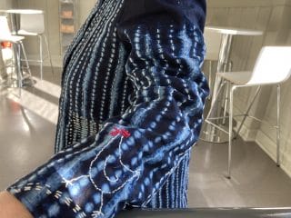 Yksityiskohta naisen batikkikankaasta valmistetusta ja kirjaillusta takista.