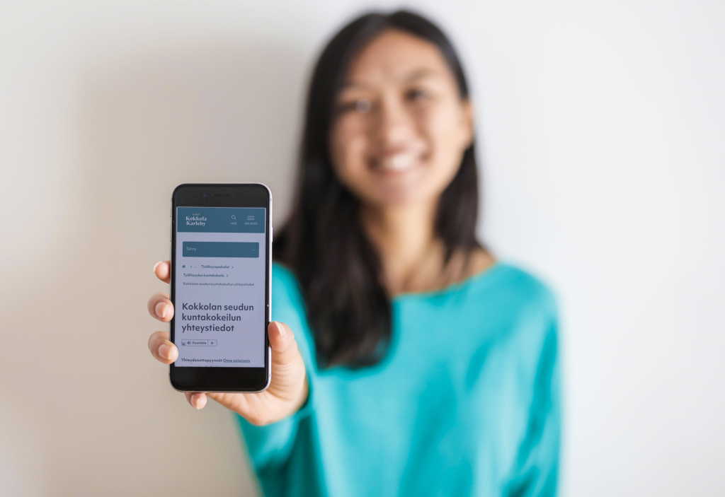 A girl is showing mobile phone´s screen at the front of her