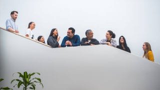 Nine young international talents at a stairs smiling and having a chat.