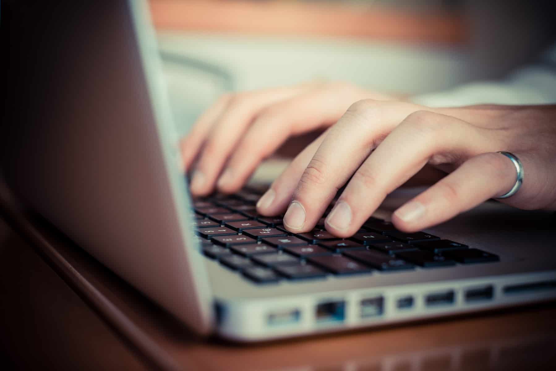 Tietokoneen näppäimistö ja kädet kirjoittamassa tekstiä