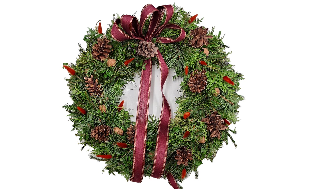 Havukranssi, joka on koristeltu kävyillä, pähkinöillä ja nauhalla.