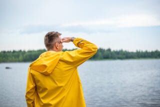 Mies keltaisessa Rukan sadetakissa katsoo kohti merta.