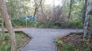 Korsning med breddning. Skyltarna styr till vänster till Rummelö-Harrbåda naturstig och till höger i riktning mot Villa Elba. 