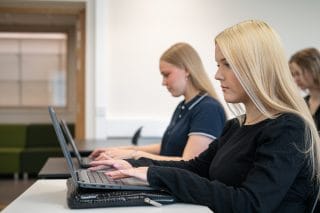 Kaksi nuorta naista opiskelee tietokoneella.