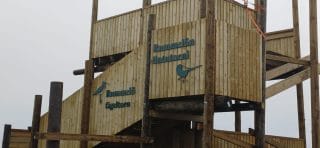 A birdwatching tower with signs on the wall.