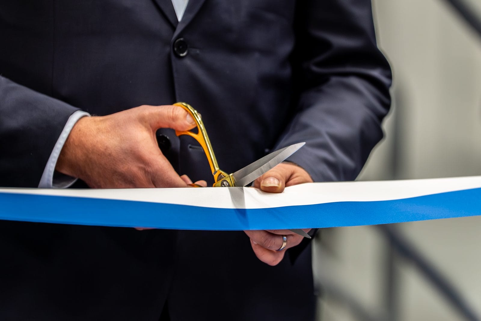 Ett blåvitt band klipps vid en invigningsceremoni.