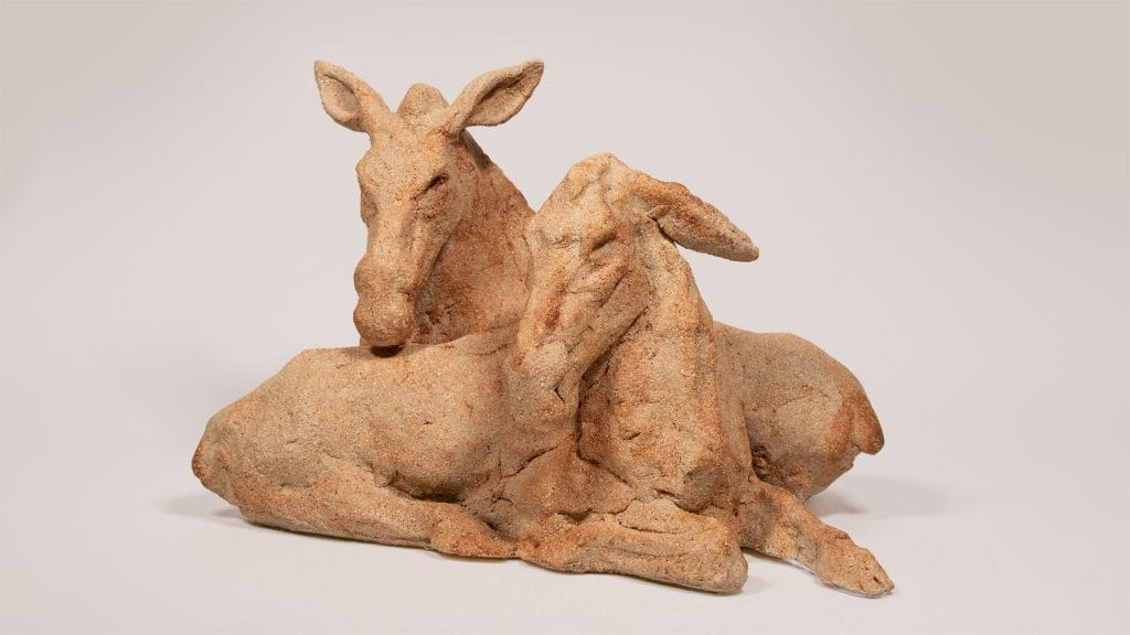 A clay sculpture depicting two moose resting side by side.