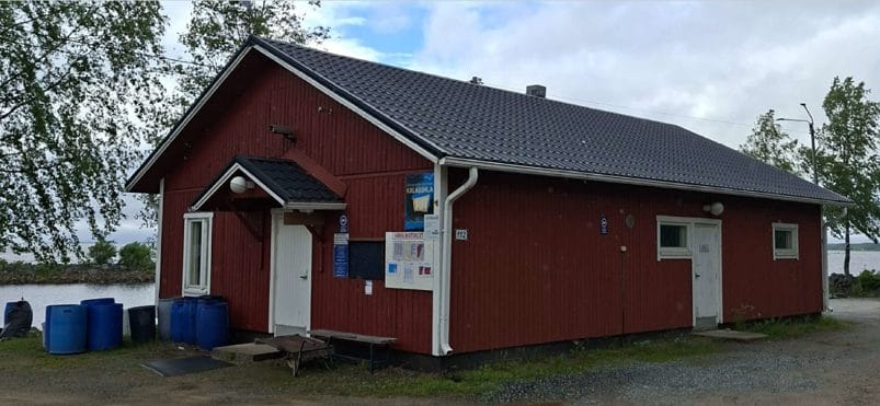 Marinkaisten kalasataman punainen laudoitettu kalahalli meren rannalla.