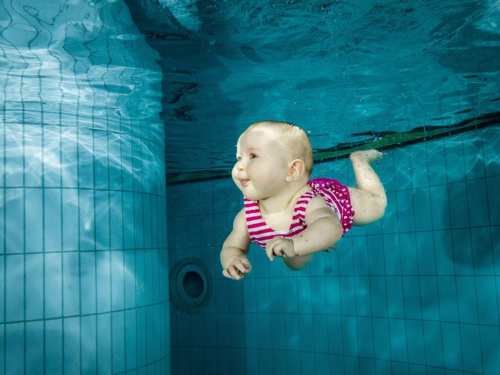 Baby dyker i simbassäng
