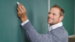 A teacher writing on chalkboard.