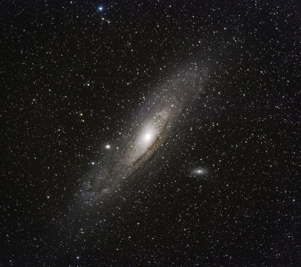 Andromedan kierteisgalaksi utuisena kiekkona yötaivaalla.