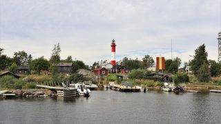 Foto taget från havet av Tankar båthamn. I bakgrunden syns trästugor på ön samt Tankars rödvita fyr.