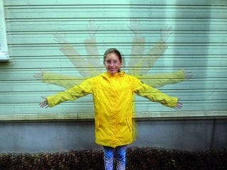 Tyttö keltaisessa takissa heiluttaa käsiä