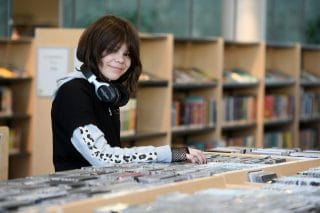 Nuori tyttö selailee kirjastossa cd-levyjä.