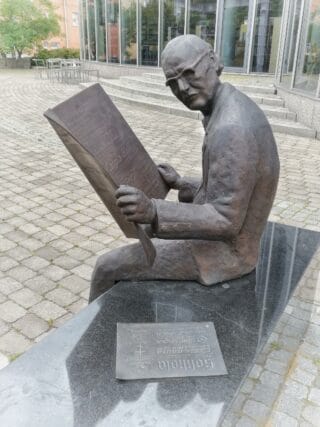 Kaija Kontulainen: Wladimir Froloff. Froloff istuu kivipenkin päällä ja lukee sanomalehteä