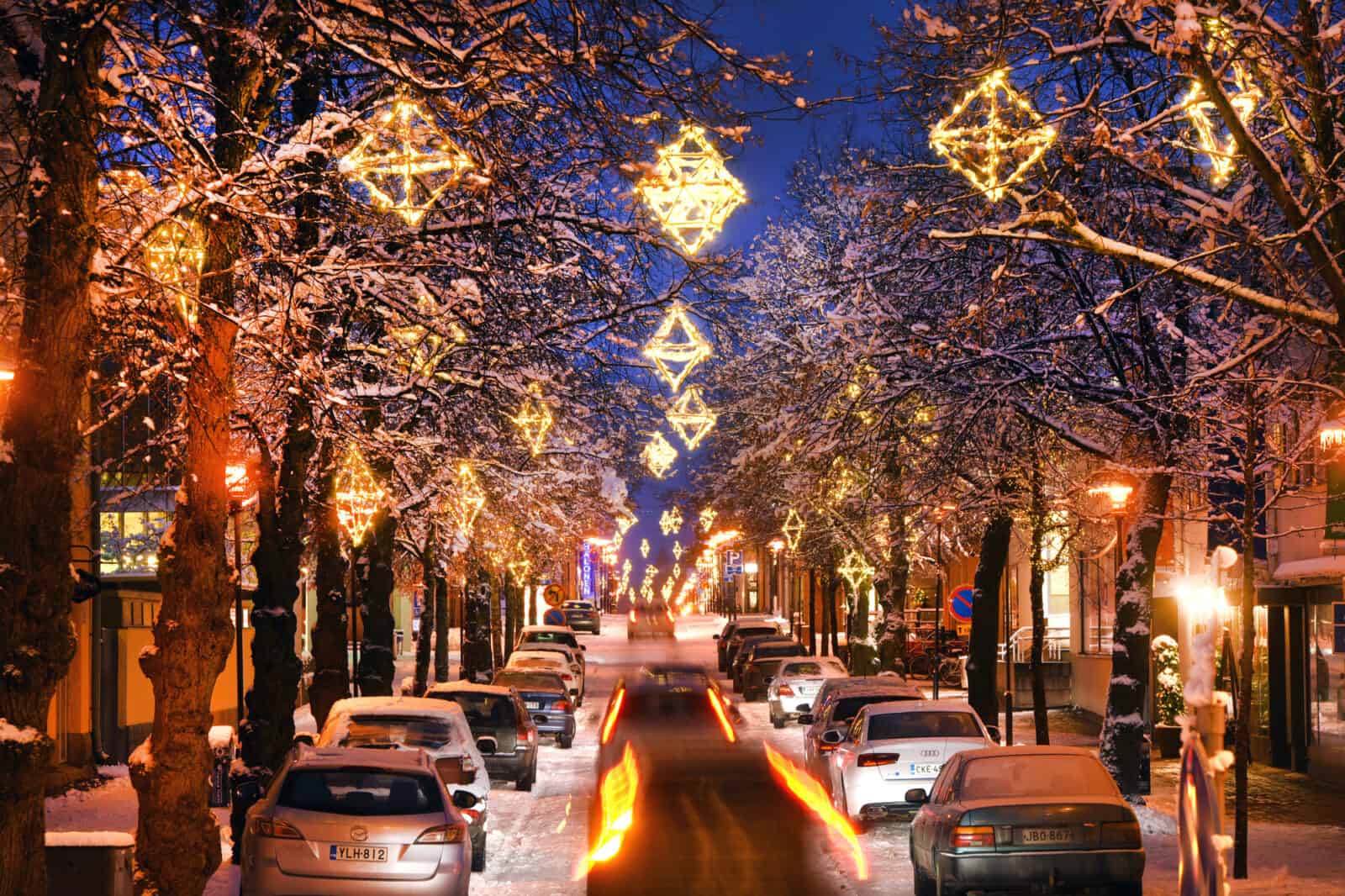 Talvinen iltanäkymä nupulakivikadulta. Katua reunustavissa puissa on himmelinmallisia, lämpimän valkoisia jouluvaloja.