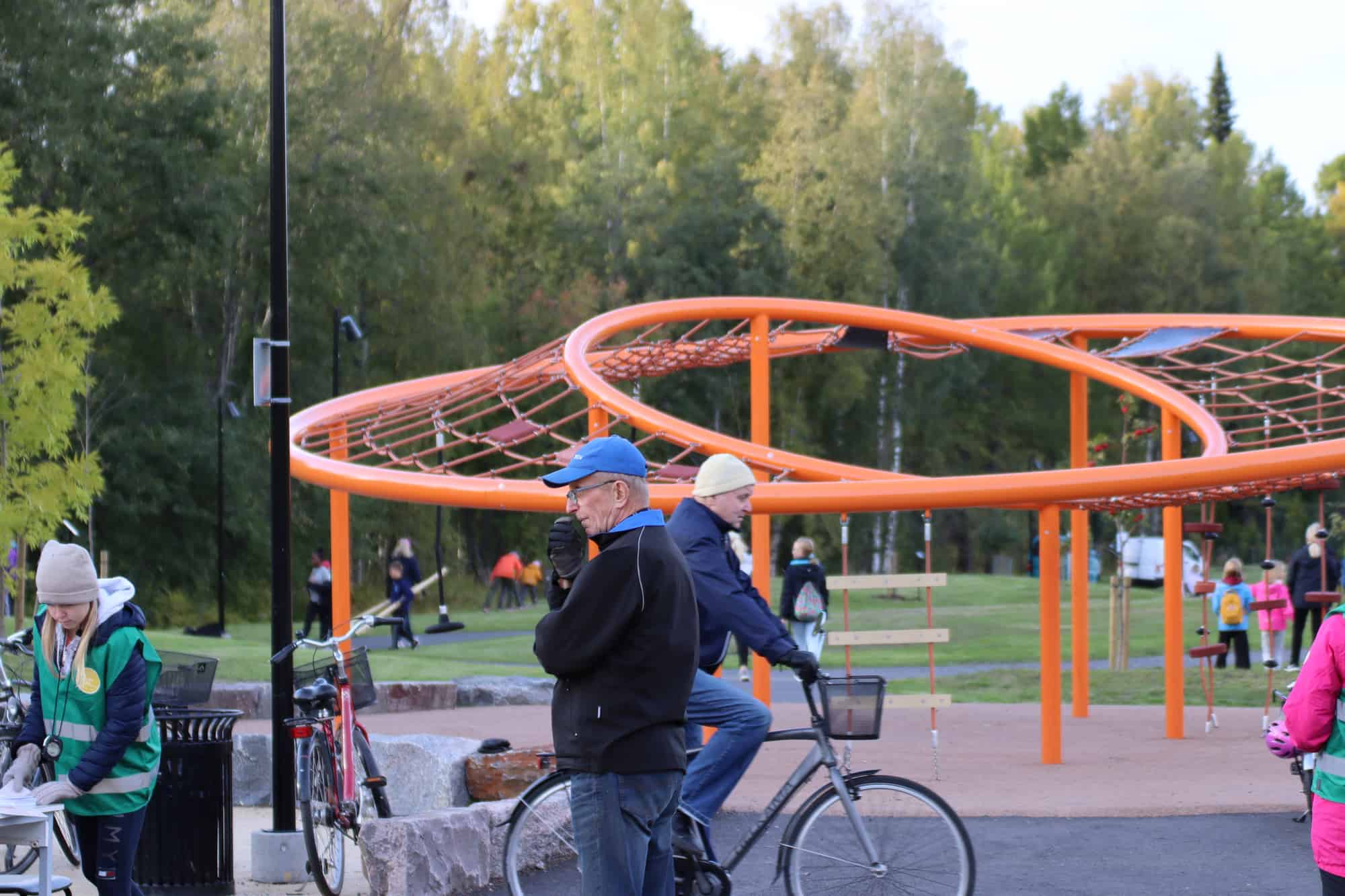 Oranssi kiipeilyteline Brita marian puistossa, edessä pyöräilijä