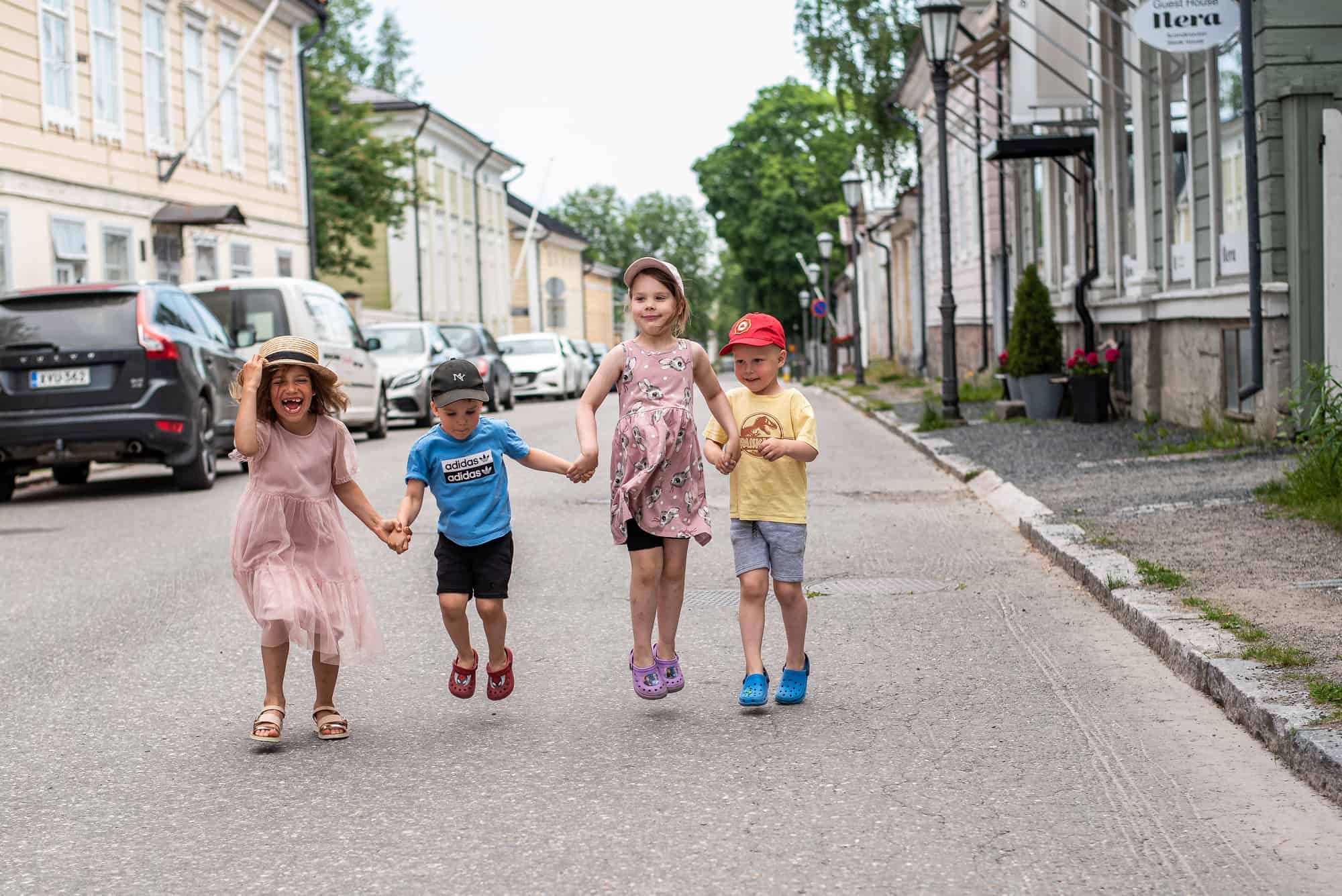 Neljä lasta käsikkäin Neristanin kadulla. Sää on kesäinen.
