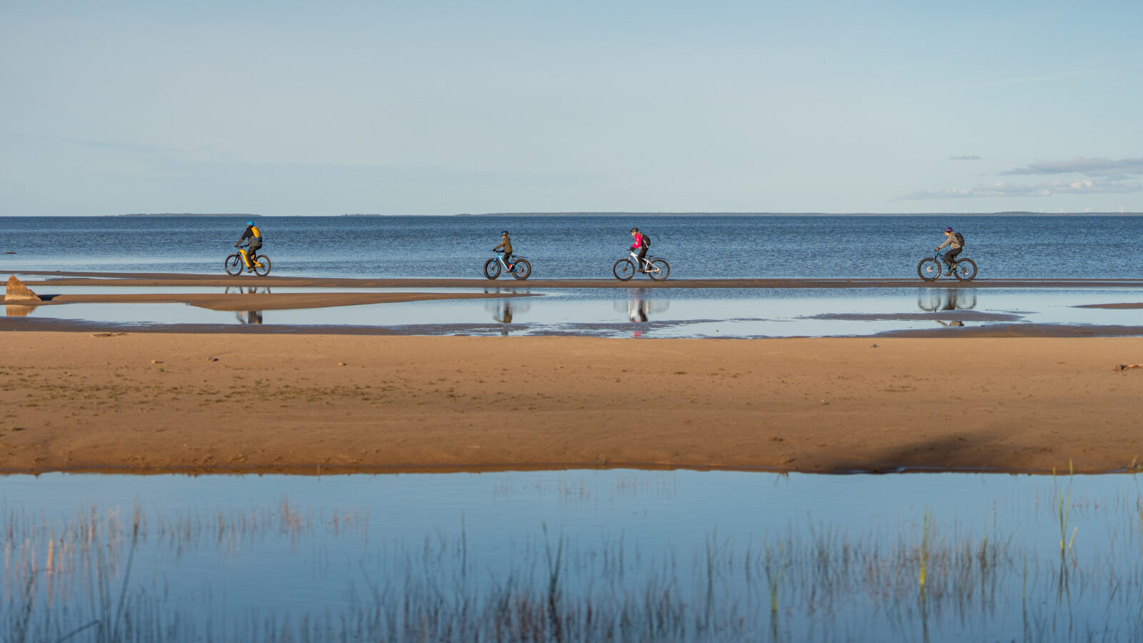 pyöräilijöitä hiekkarannalla